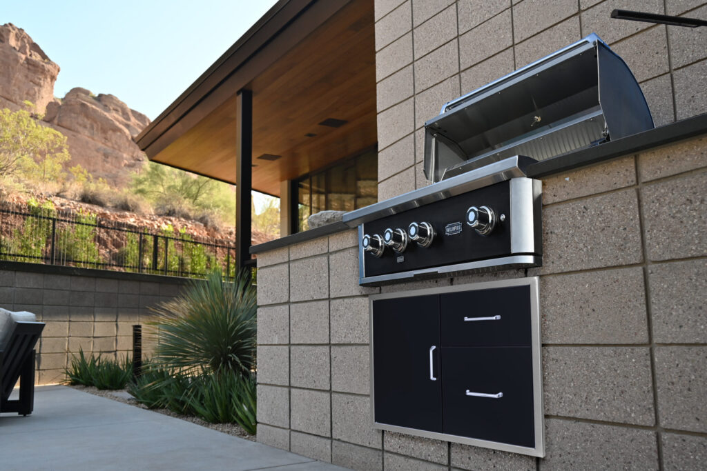 A Wildfire Outdoor Living built-in grill open on a patio island