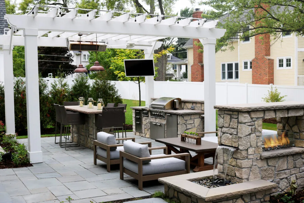 A completed backyard oasis with a pergola, outdoor kitchen, and fire feature
