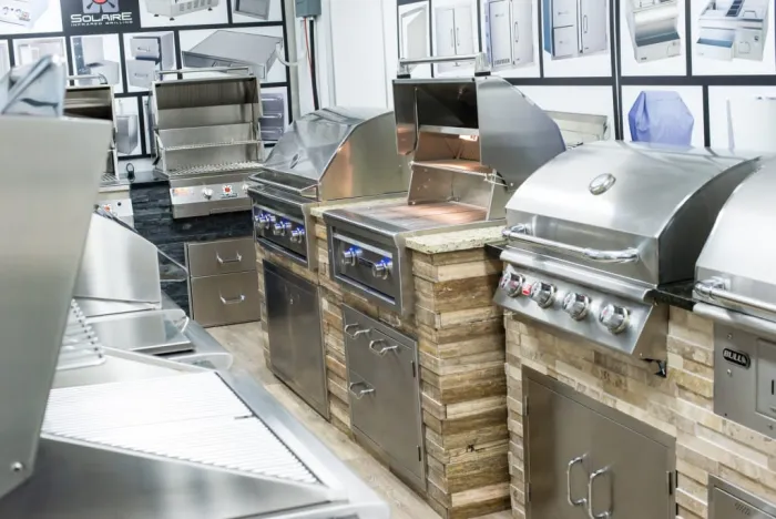Solaire and Bull grills built into stone islands with an open hood and side burner